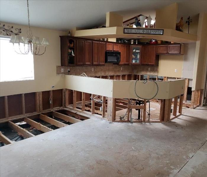 A kitchen missing lower part of cabinets and drywall. No carpet and some floor missing. 